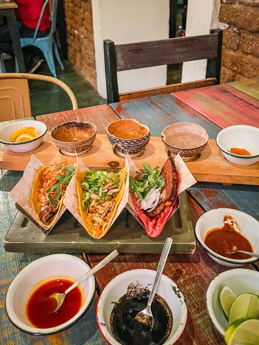 tacos on a table with salsas and mezcal