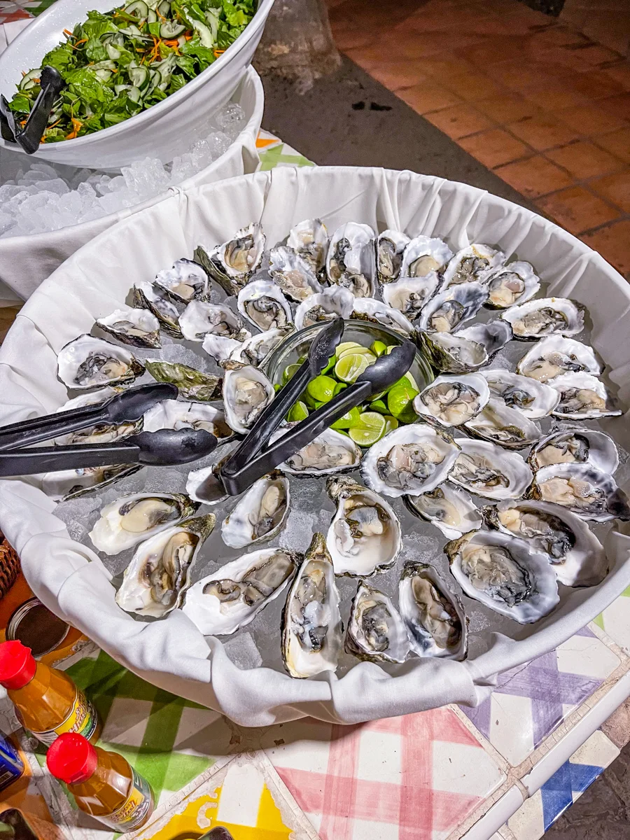 bowl full of shucked oysters in their shells fanning out from the middle where there is a bowl of lime halves.