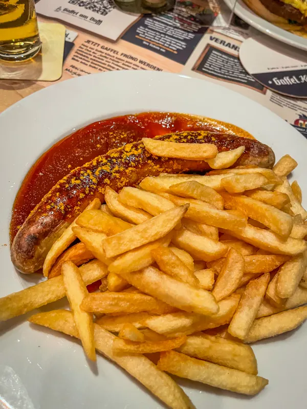 currywurst and fries on a big white plate