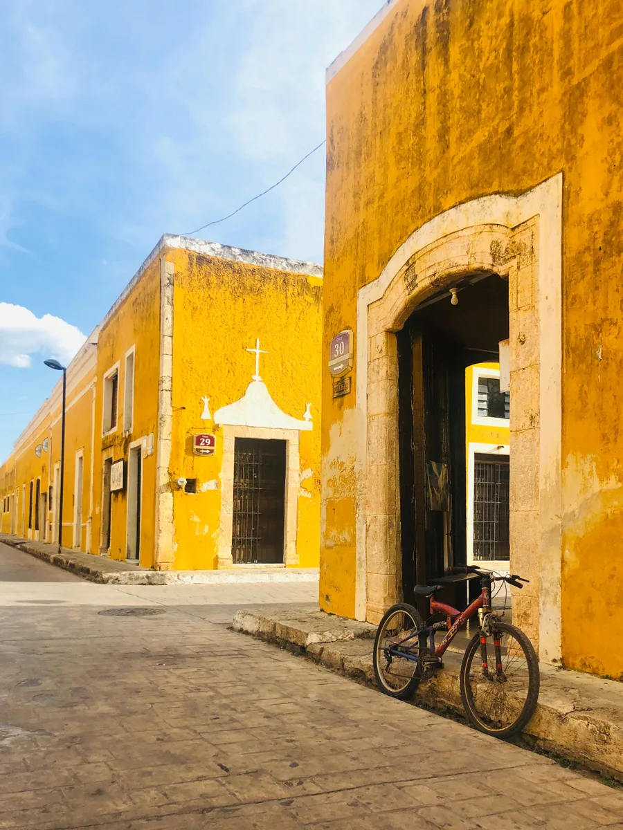 bicycle in front of a yellow building with another yellow building in the background.