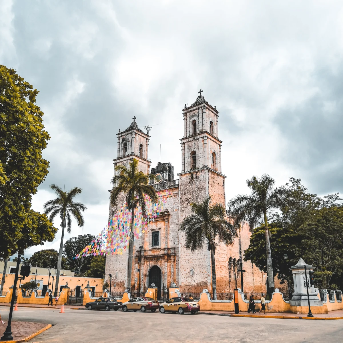 church with palm trees in front and an open square in valladolid, one of 7 pueblos magicos in yucatan.