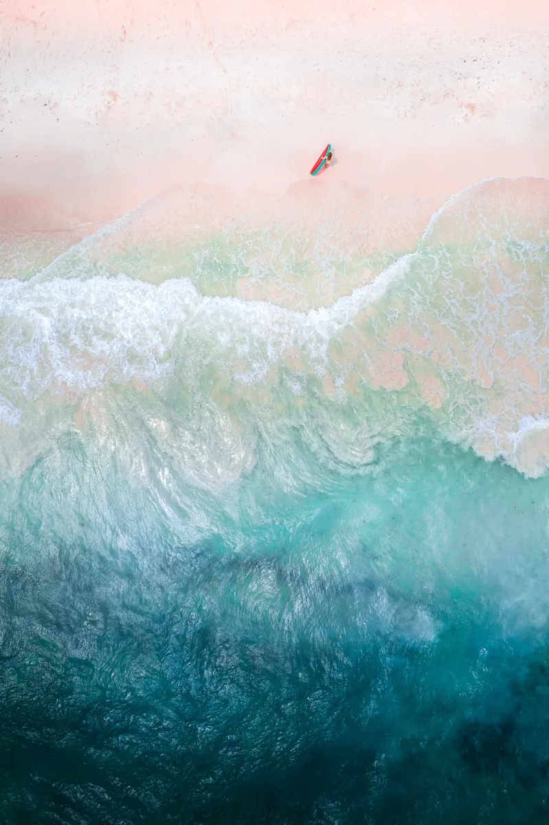 drone shot of the beach with one person standing on the sand and the ocean crashing to the shore during one of the best time to visit Cancun.
