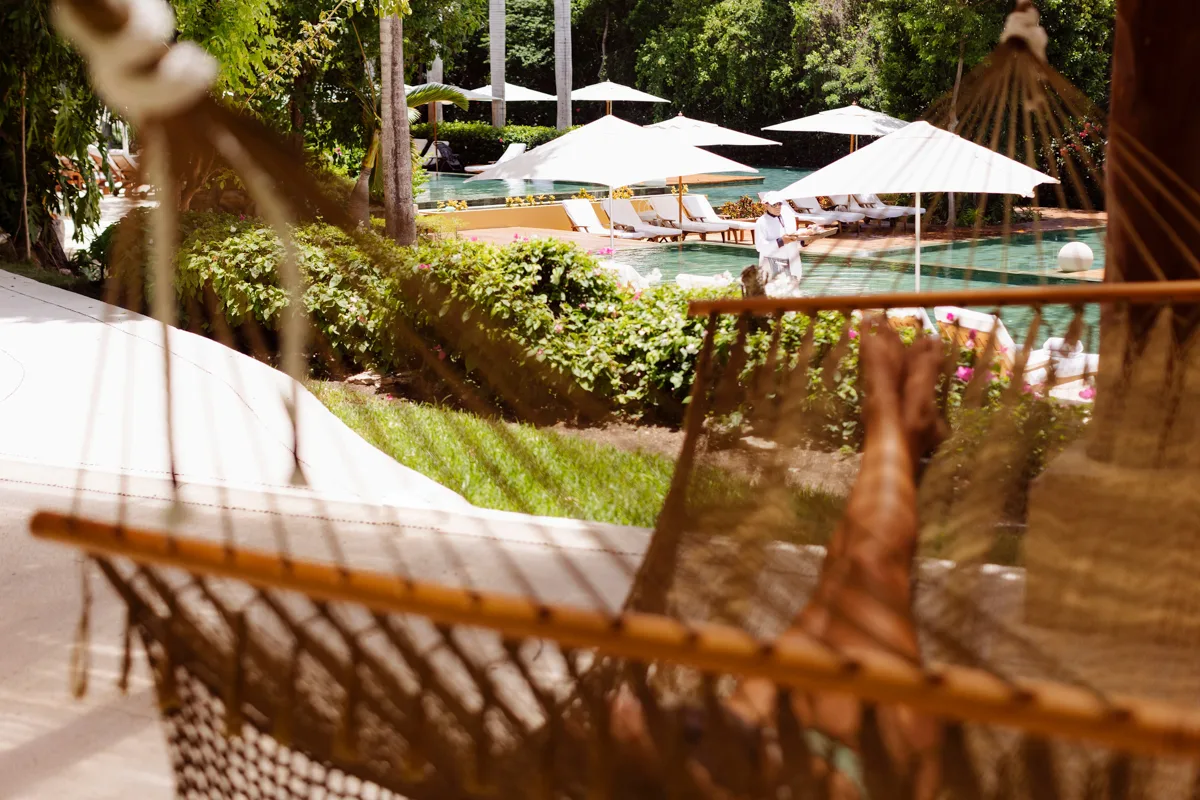 woman sitting in a hammock with pool in the background.