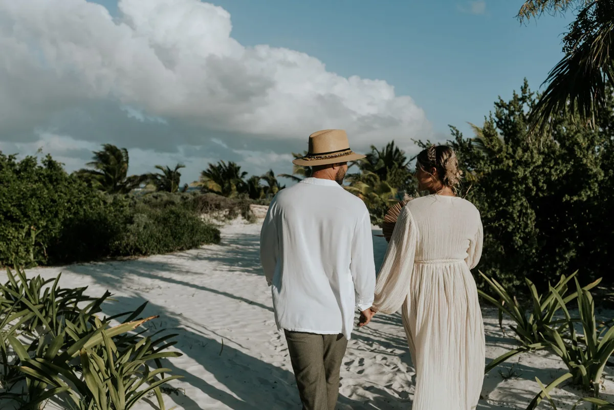 two people holding hands and walking on the beach.