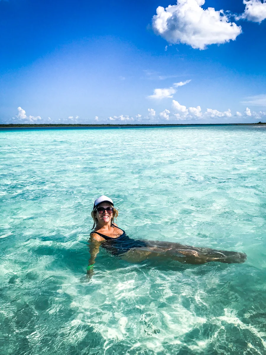 woman sitting in clear water with blue skies.