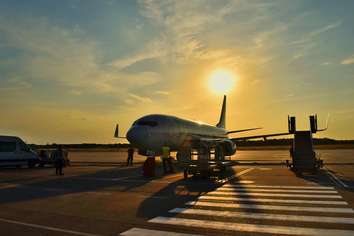 airplane on the tarmac with sun setting behind it.