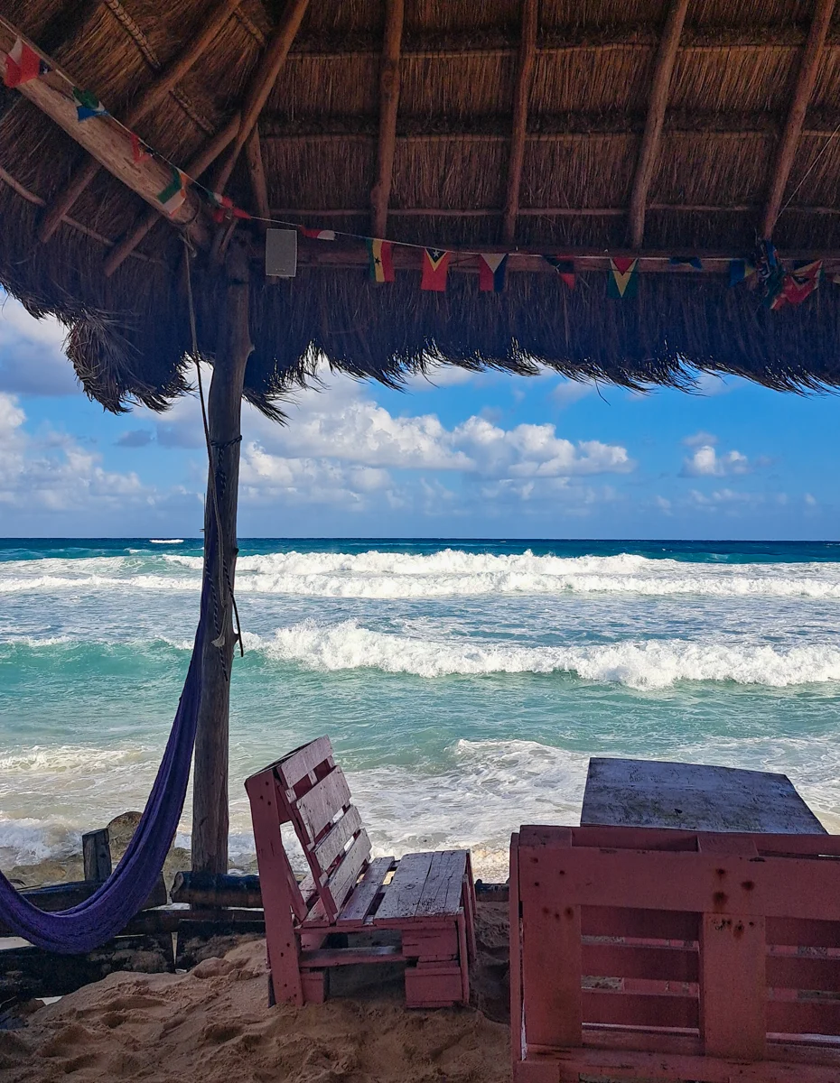 beach bar with a table under a palapa umbrella and the ocean in the background. It's one of the best things to do in cozumel if you have your own car to explore.