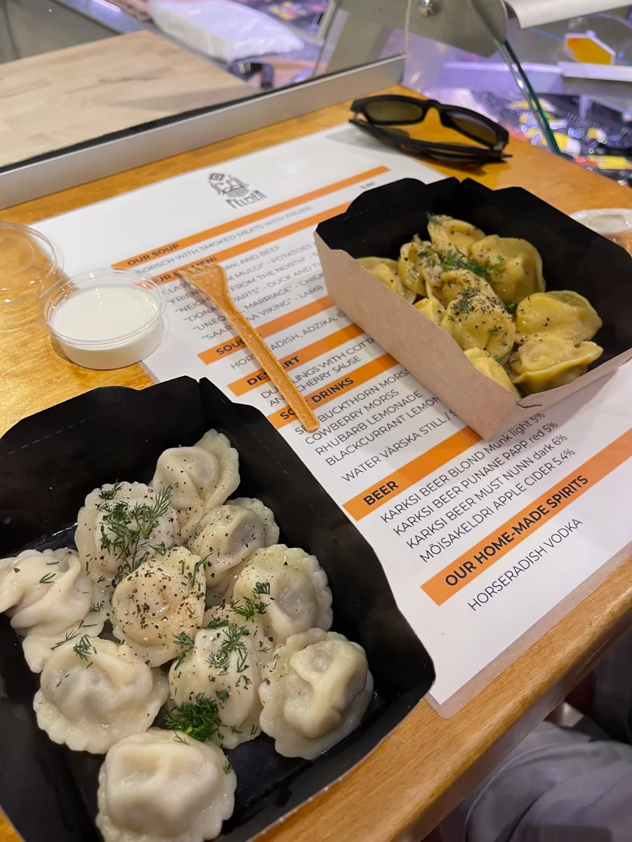 two plates of dumplings at a small market counter.