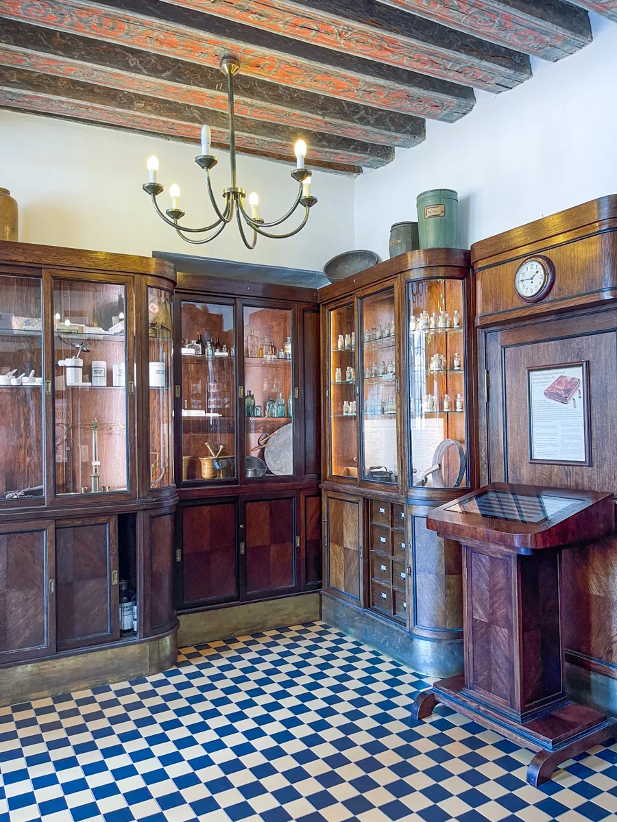 inside of an old pharmacy with wooden cabinets and tiled floor.