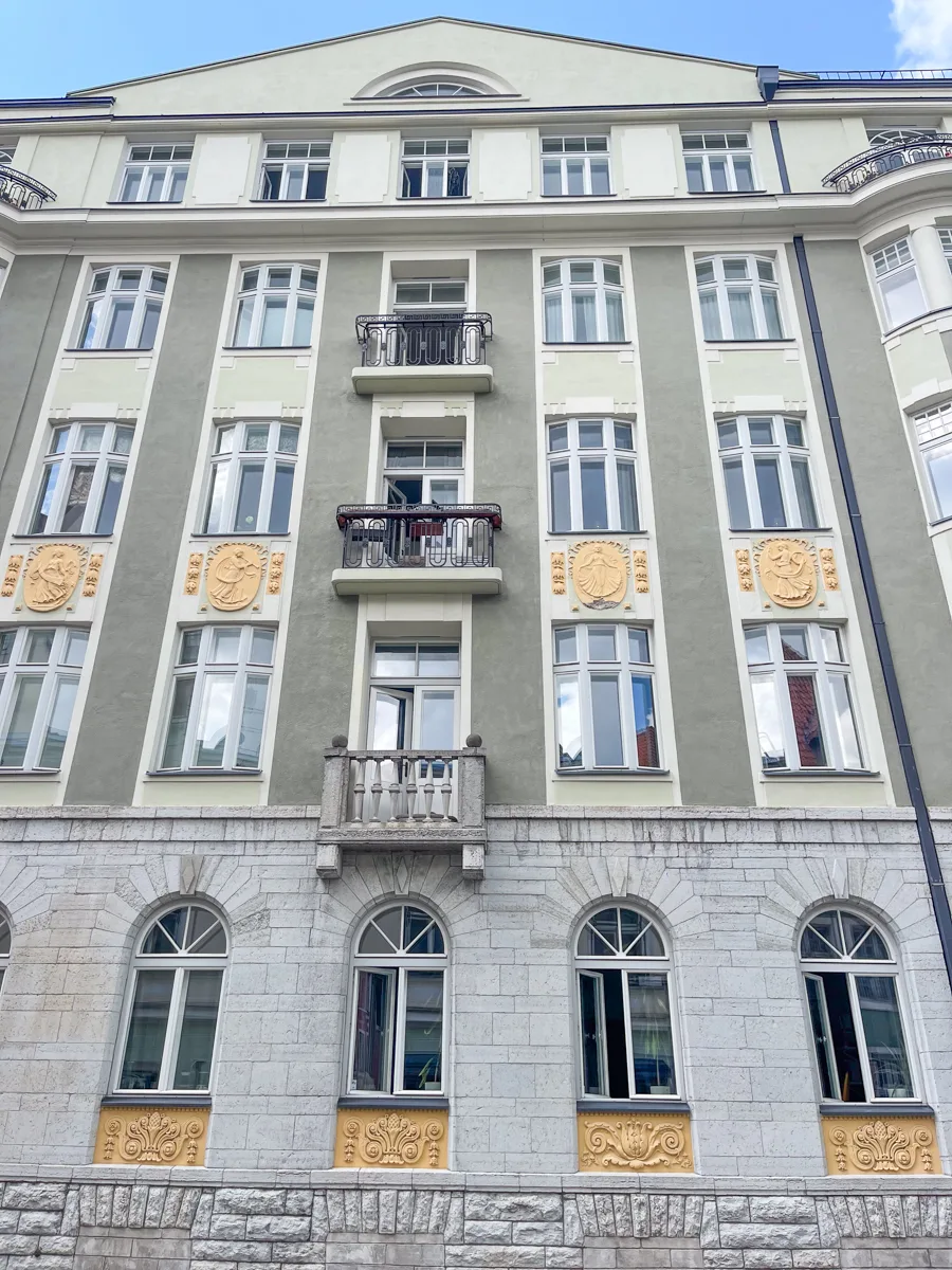 grey apartment building with balconies in the middle and windows on every floor.