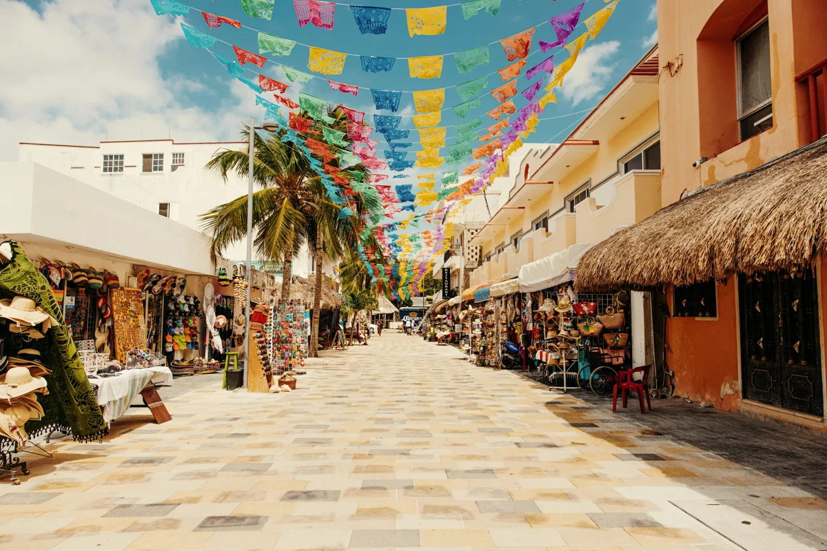 main street in playa del carmen with papel picado colorful paper flags floating above the street.