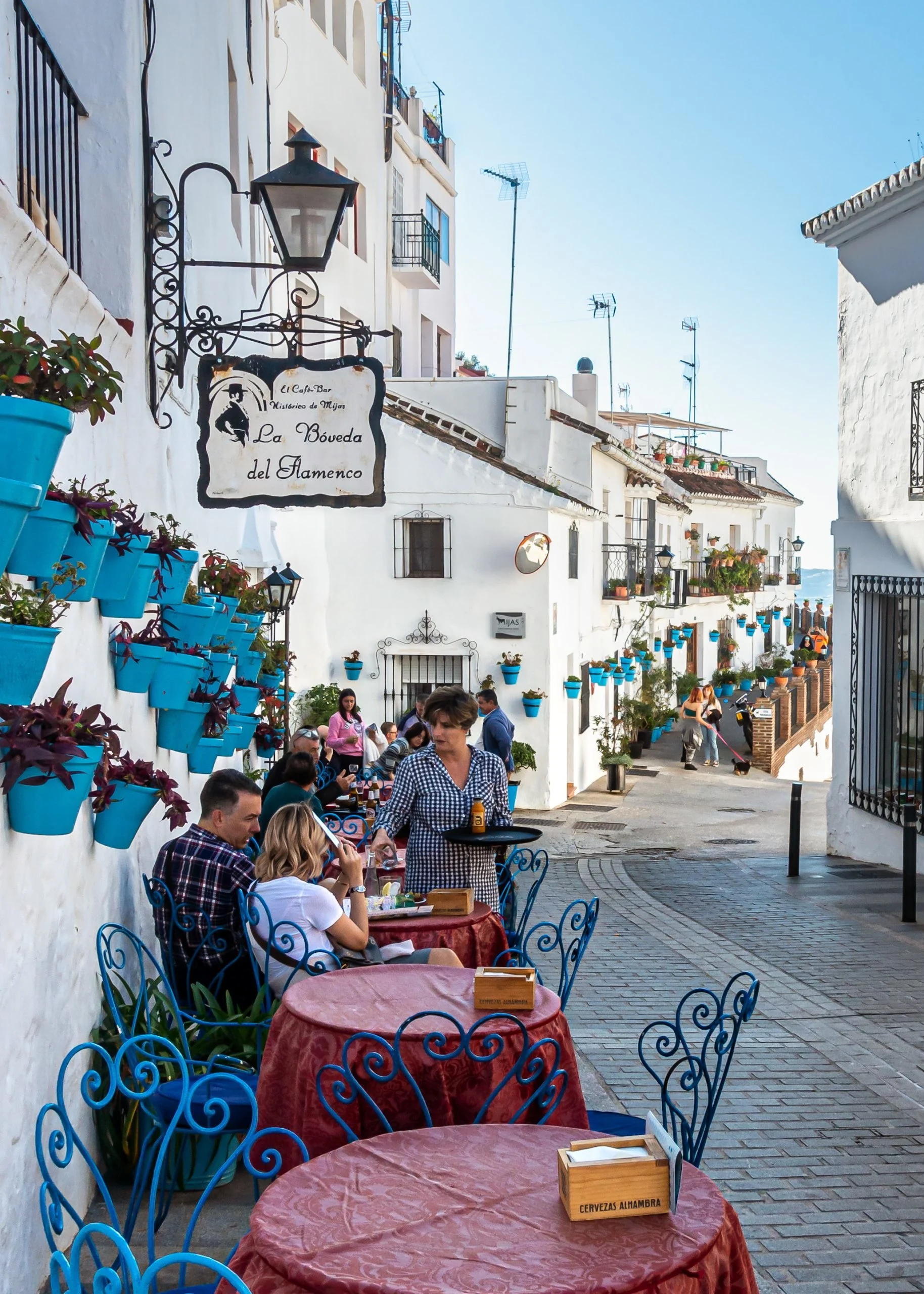 tables outside on the street in front of white painted restaurants.