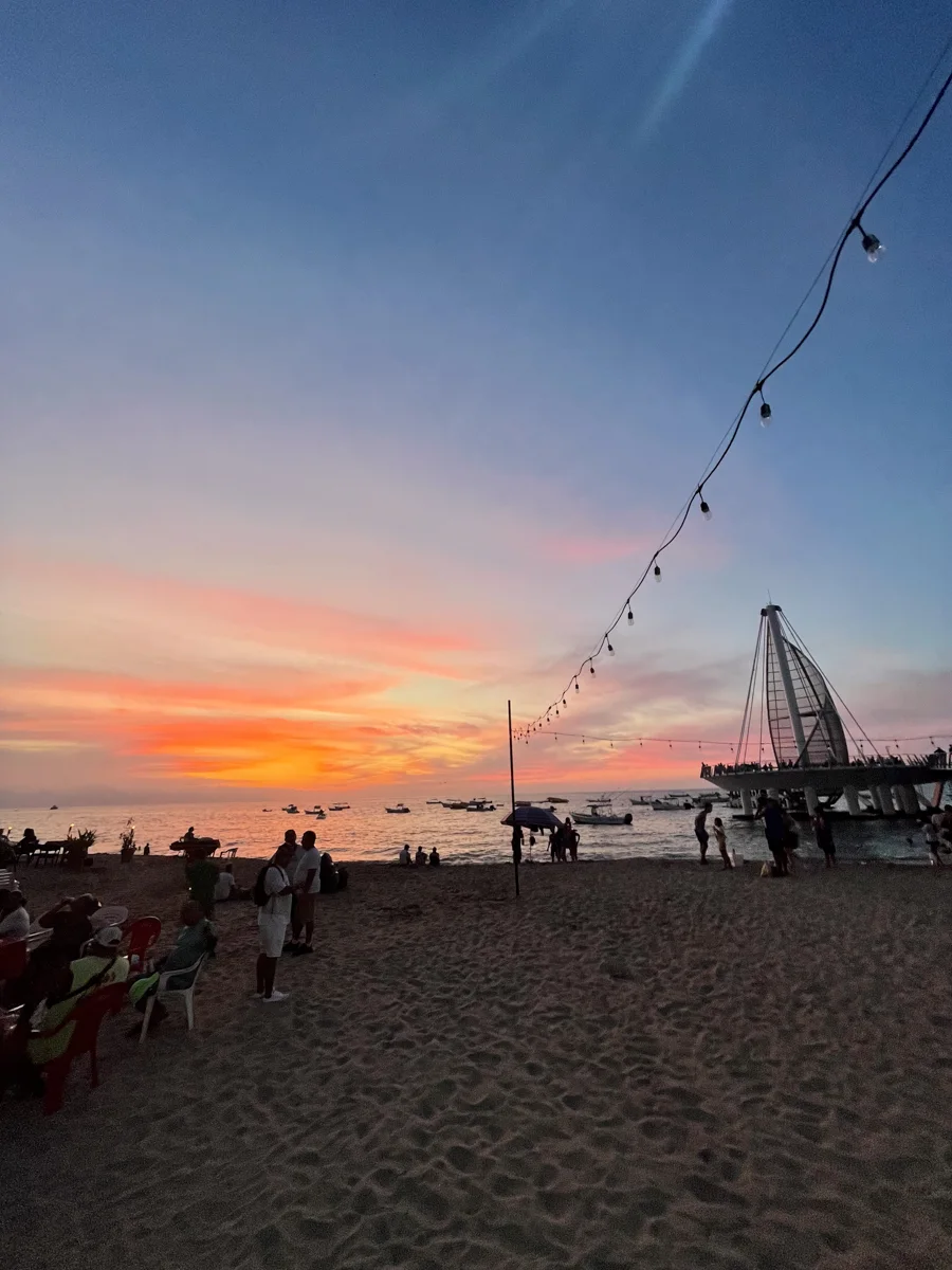 sunset over the beach with the pier in Puerto Vallarta in the distance.