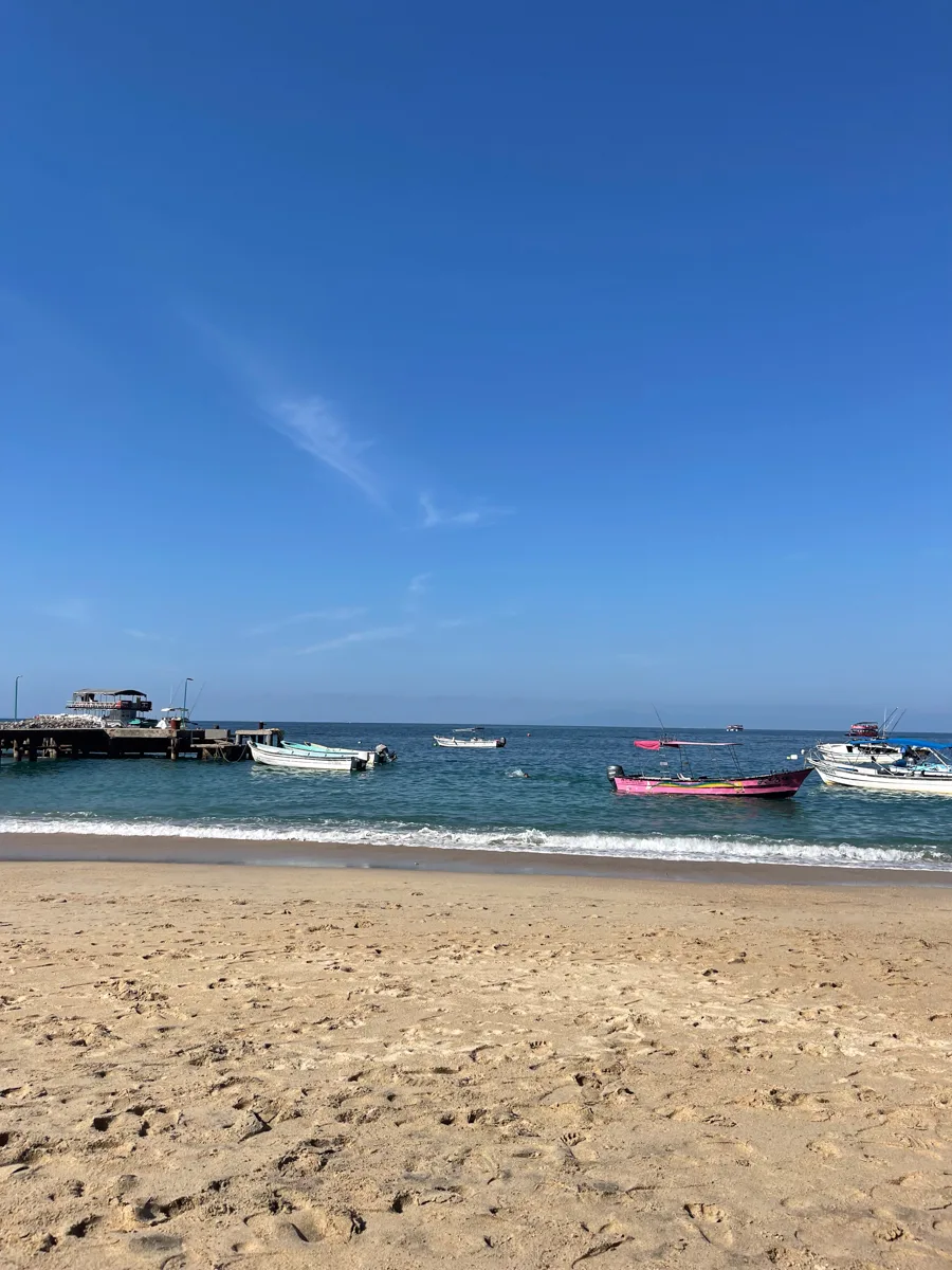 beach with boats sitting in the water.