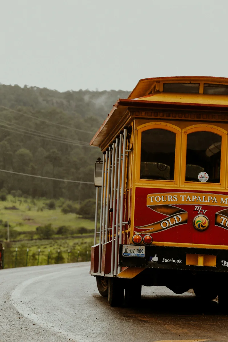 tram that is yellow and red driving on a foggy road. The tram says Tapalpa, one of the pueblos magicos in Jalisco