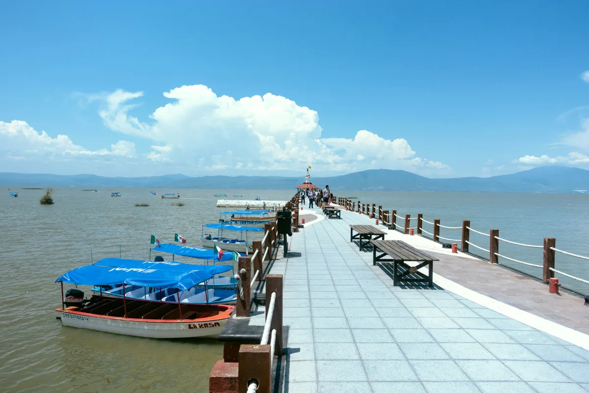 lake chapala with small boats moored to a long boardwalk.