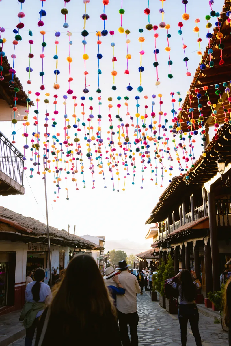 long street with strange of colorful pom poms hanging over it at one of the pueblos magicos in Jalisco.