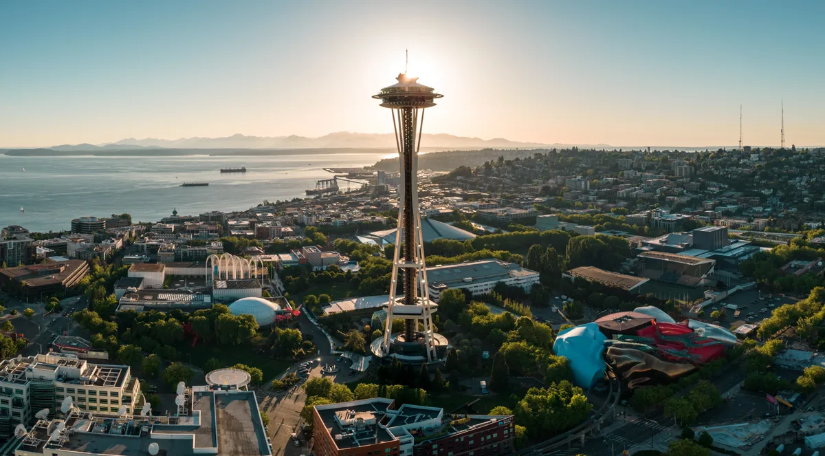 aerial view of seattle with the space needle in the center and the sun behind it.