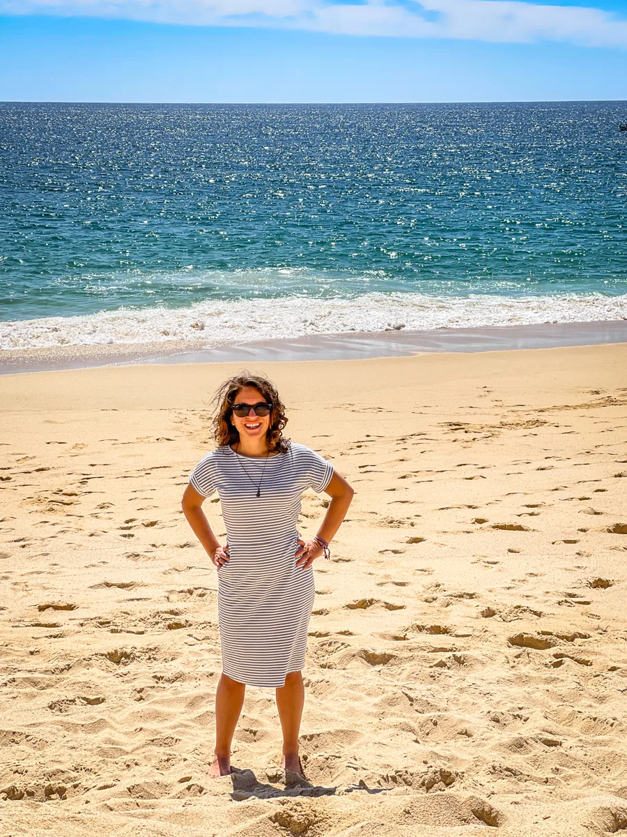 woman standing on the beach with ocean in the background.