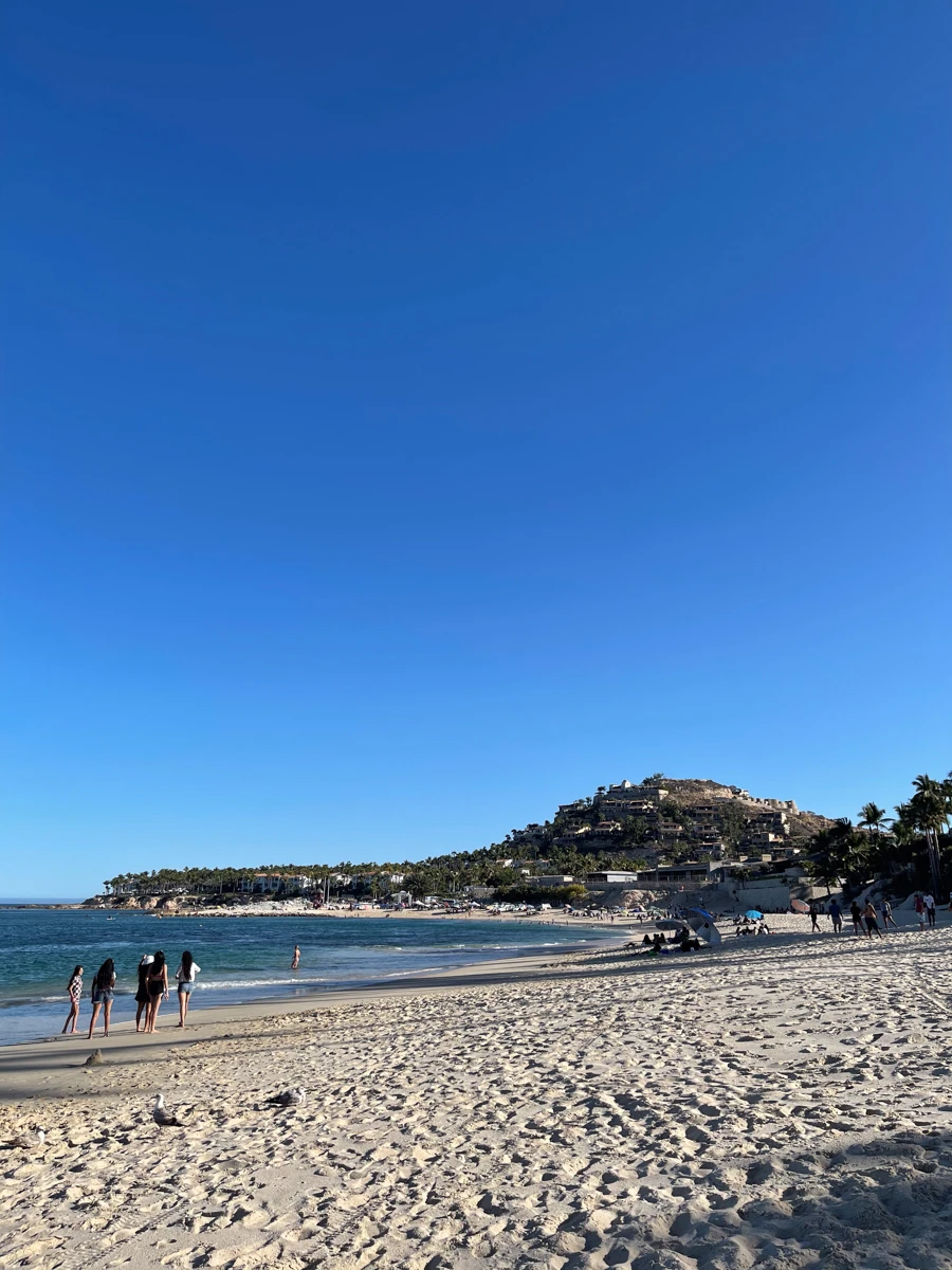 Costa Azul beach in San Jose del Cabo, a long sandy beach with mountains in the distance and people walking on the beach.