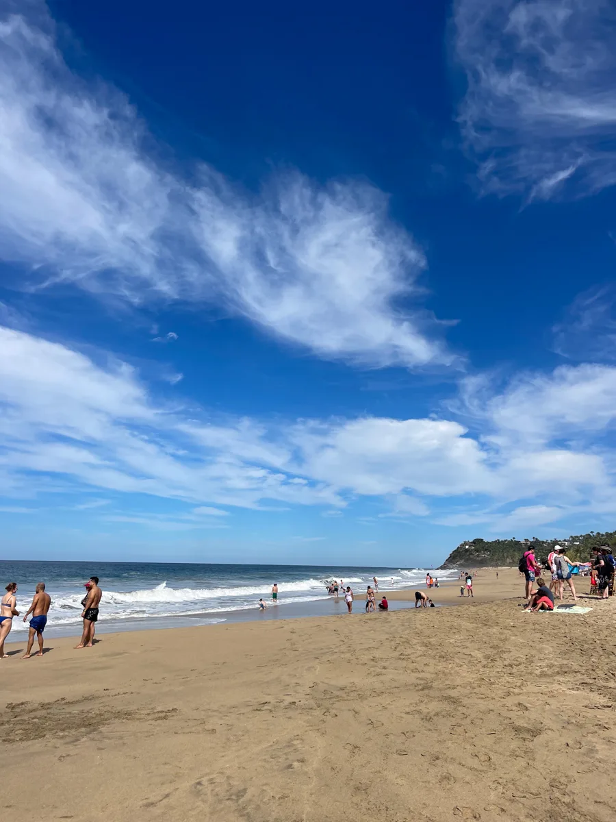 long sandy beach with hills in the background.