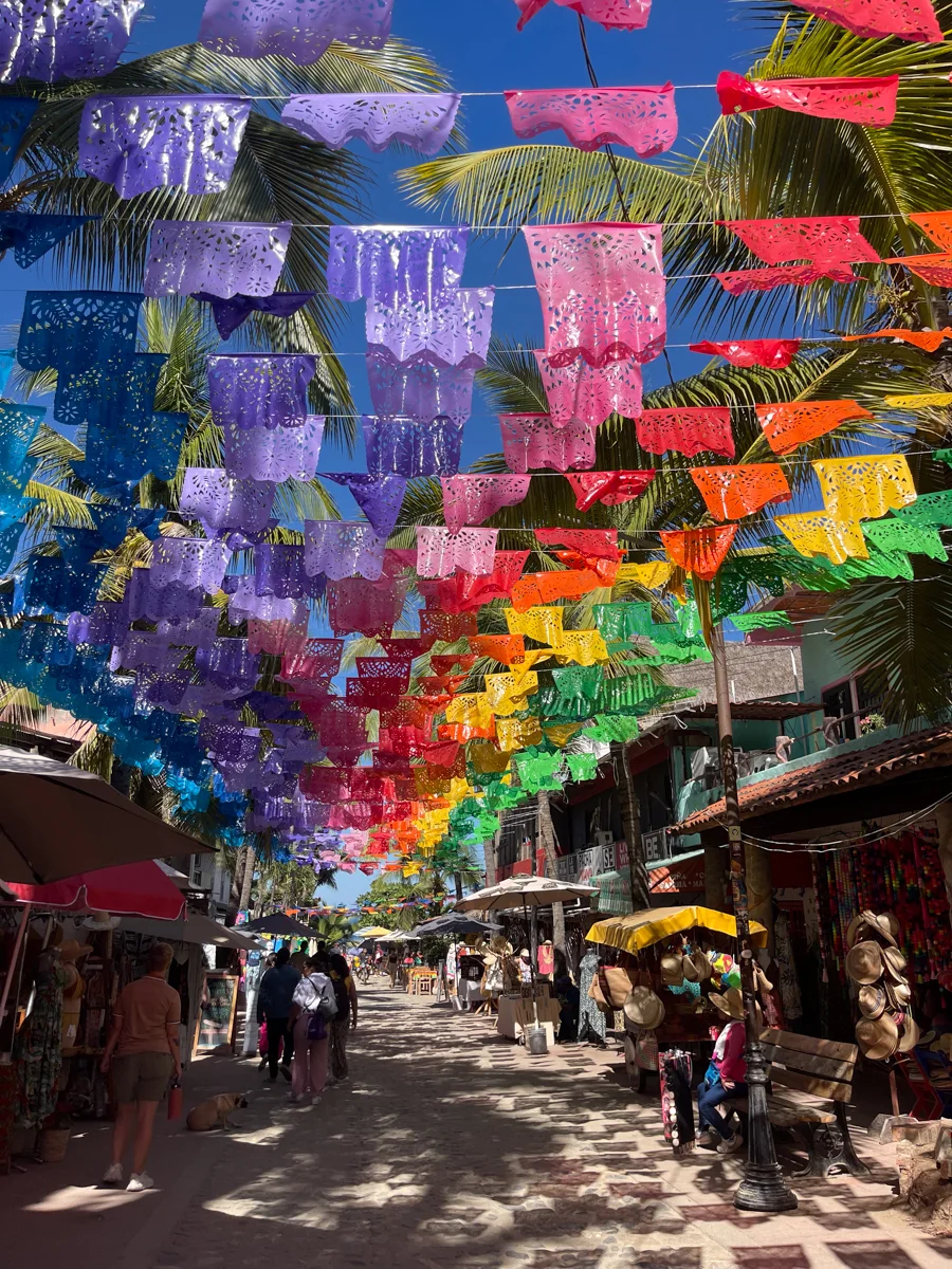 street with colorful flags over it in one of the best beaches in Nayarit, Sayulita.
