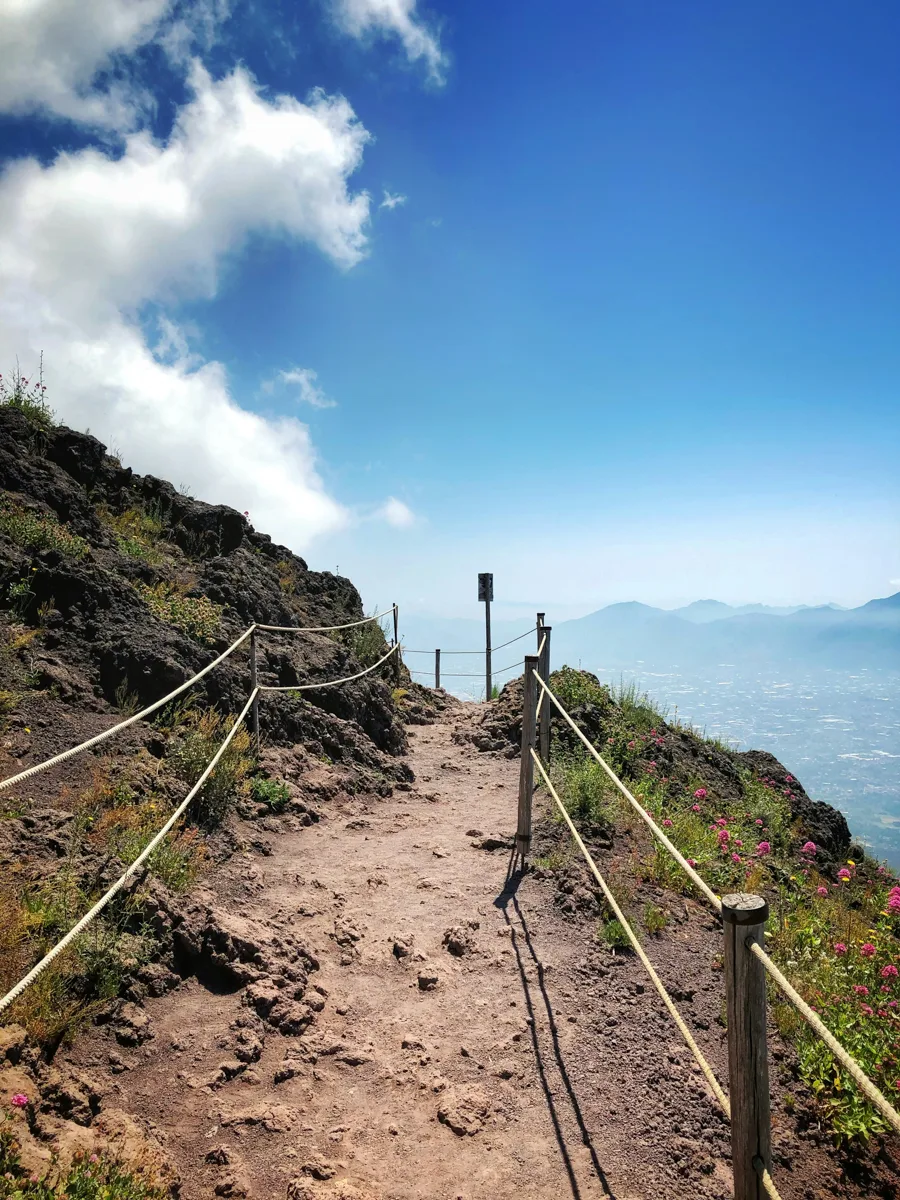 hiking trail with blue skies and a cloudy horizon in the distance.