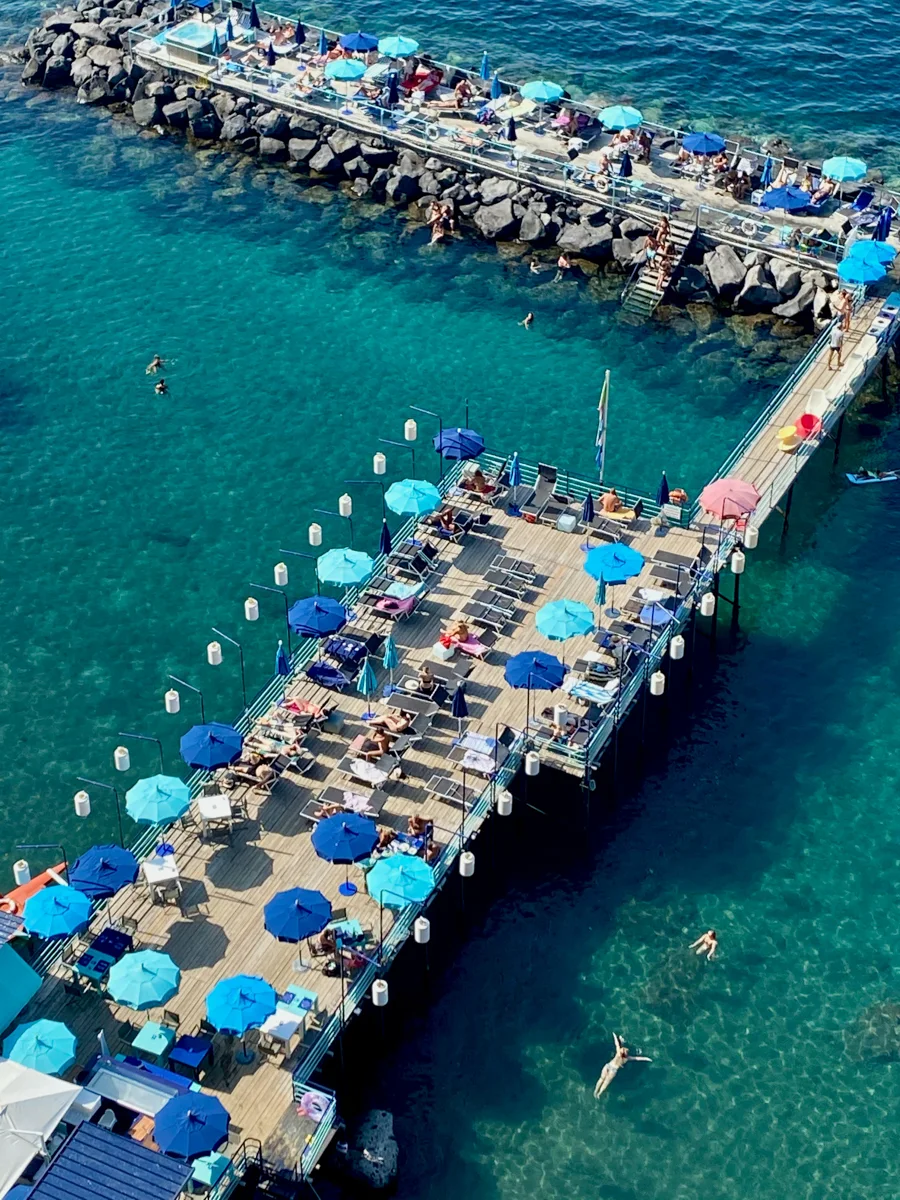 sorrento beach on the boardwalk with blue umbrellas photographed from above.