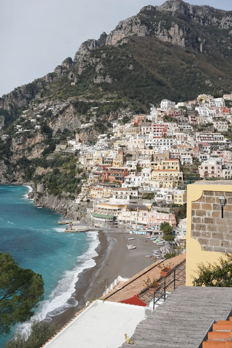 beach in positano with white houses in the background creeping up the hill.