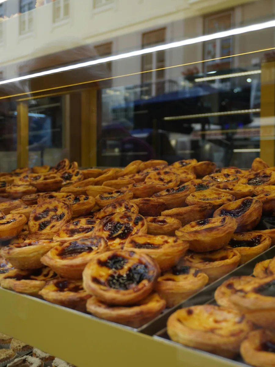 rows of pastel de nata inside a case at a bakery in lisbon portugal.