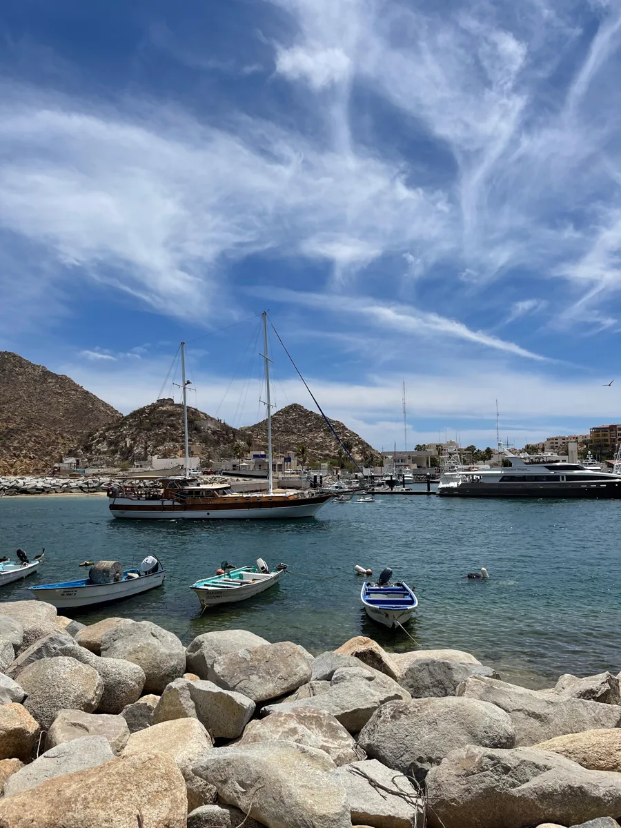 harbor with a few boats moored in the water and mountains in the background.