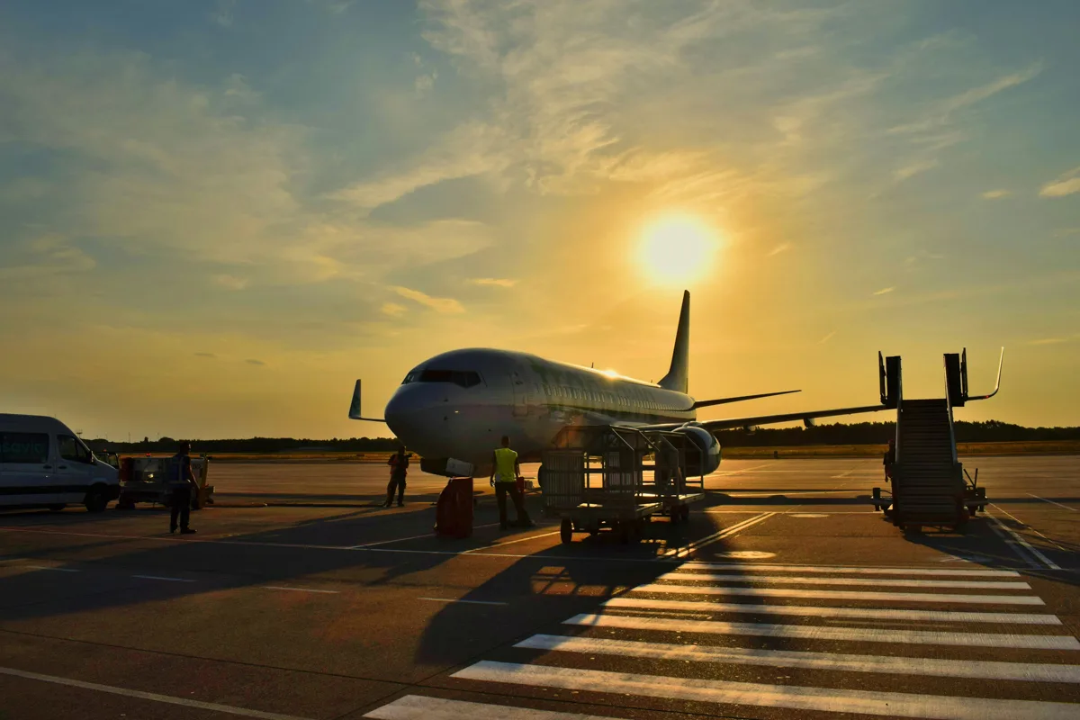 airplane on the tarmac with the sun setting behind it.