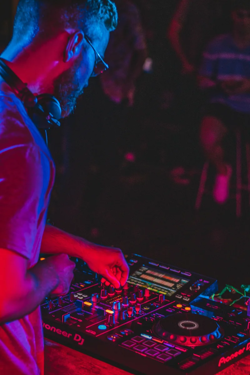 dj mixing on a table with purple and blue light shining on him.