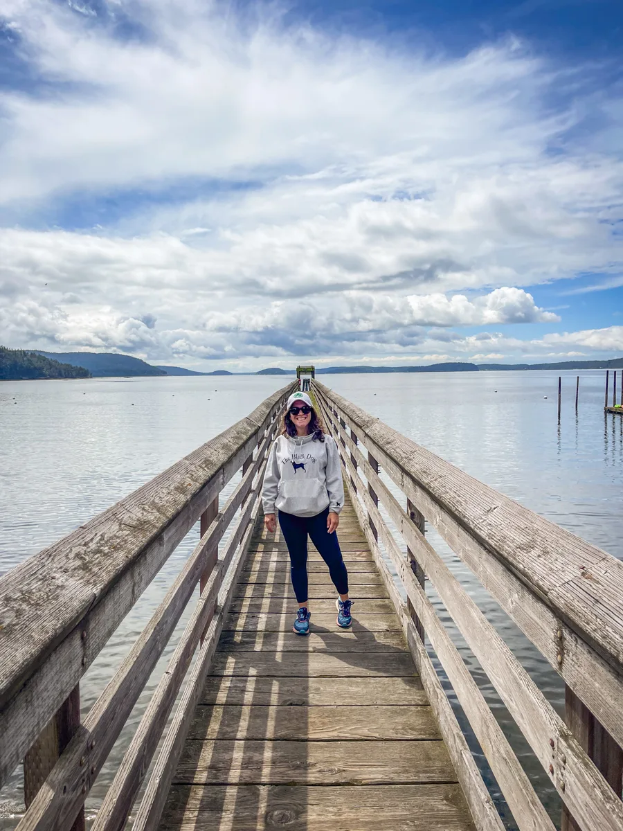 woman standing on a bridge with the water on both sides and clouds on the horizon.