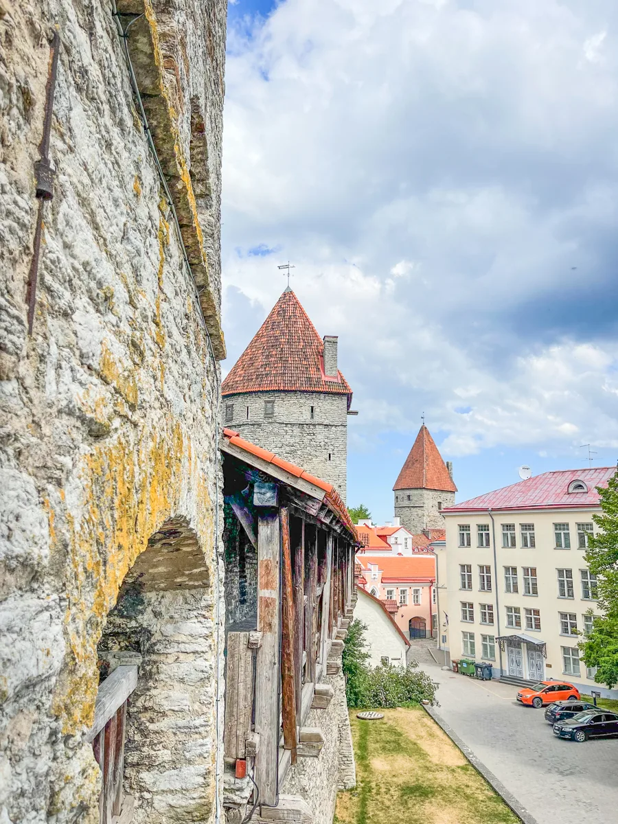side image of a historical city wall with a tower in the middle and another tower across the street in the distance.