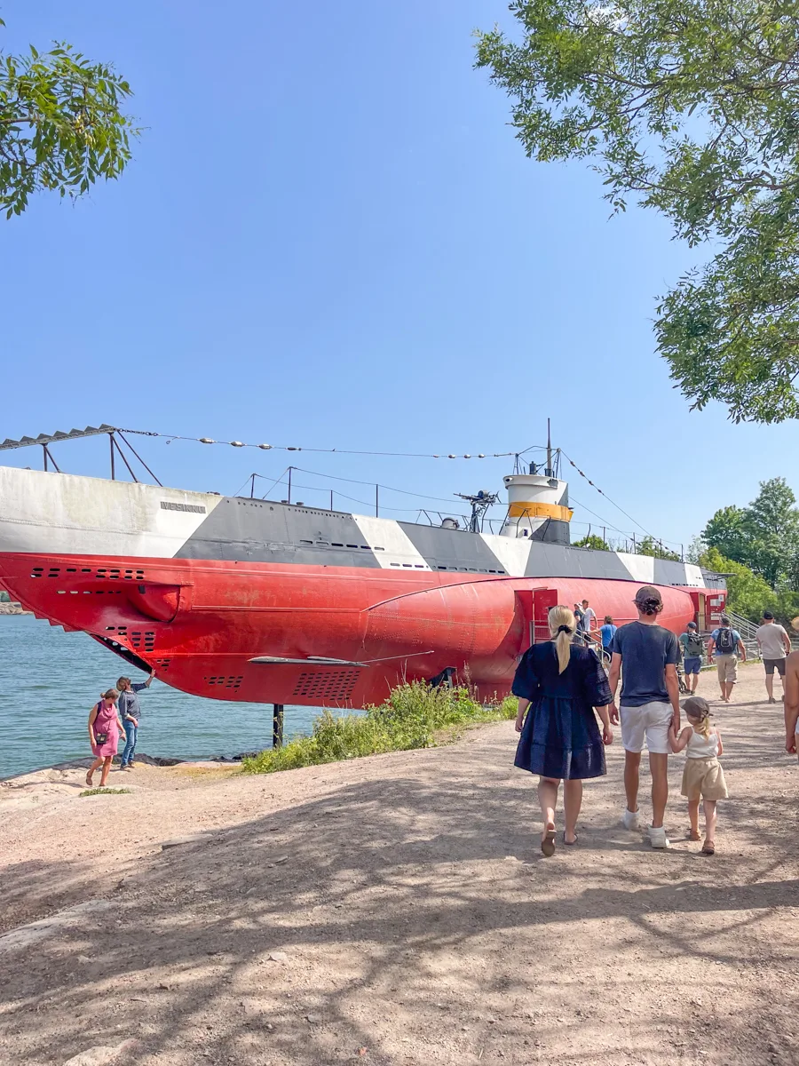 a submarine just out of the water with a few people walking past it.
