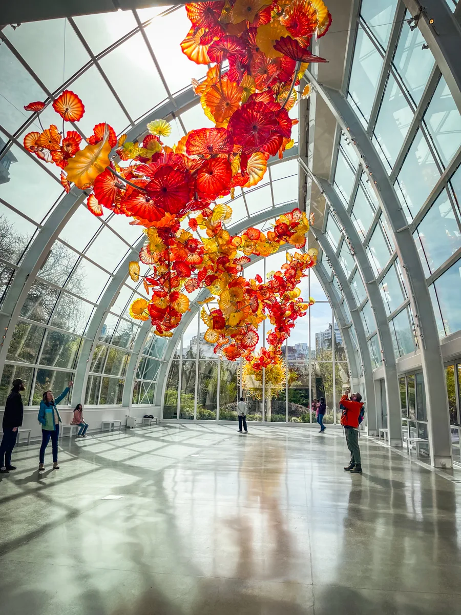 Inside of the Chihuly Garden and Glass museum in Seattle with a huge red and yellow art installation inside of a glass greenhouse.