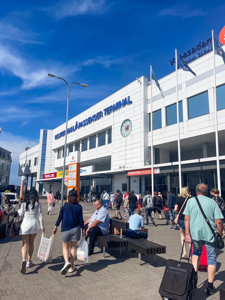 entrance to the ferry terminal in Tallinn where you catch the ferry to Helsinki with people filing into the white building with luggage.