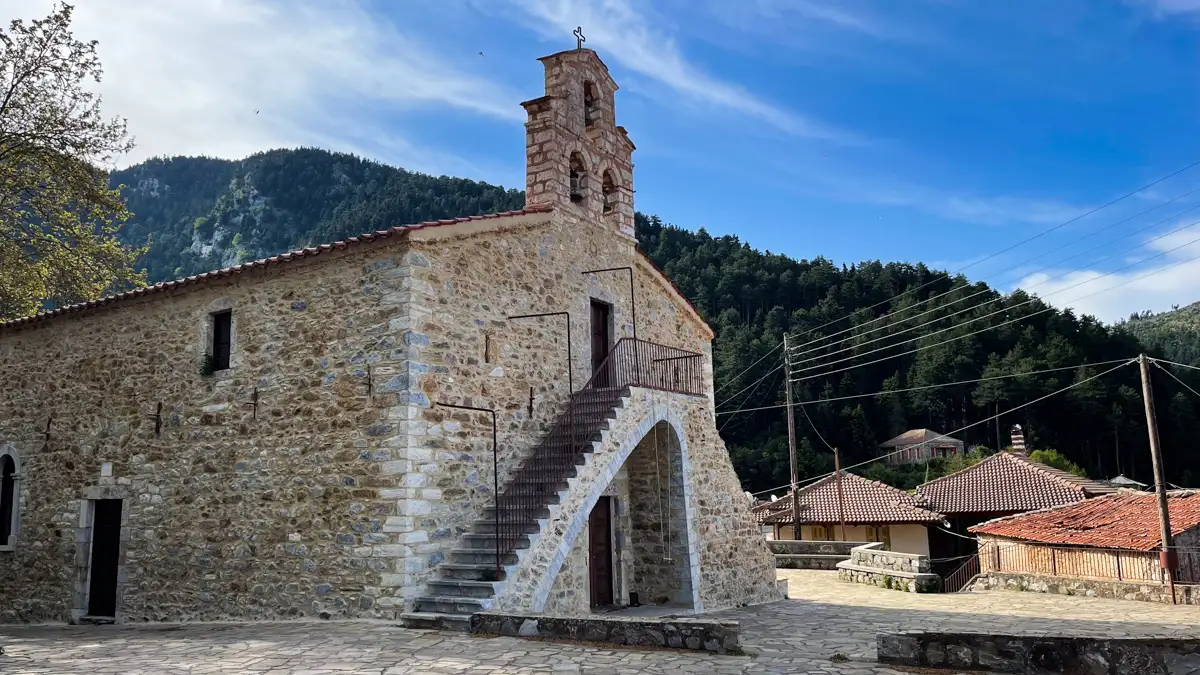 church in front of mountains and bright blue skies above.