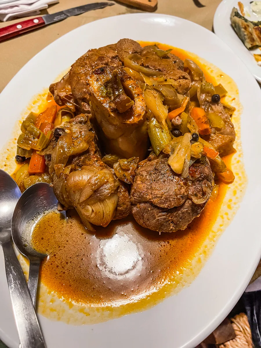 plate of meat slowcooked like a stew with gravy and vegetables surrounding it.
