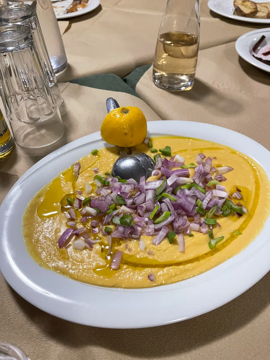a plate of whipped up hummus-like dip topped with red onion and half a lemon on the side.