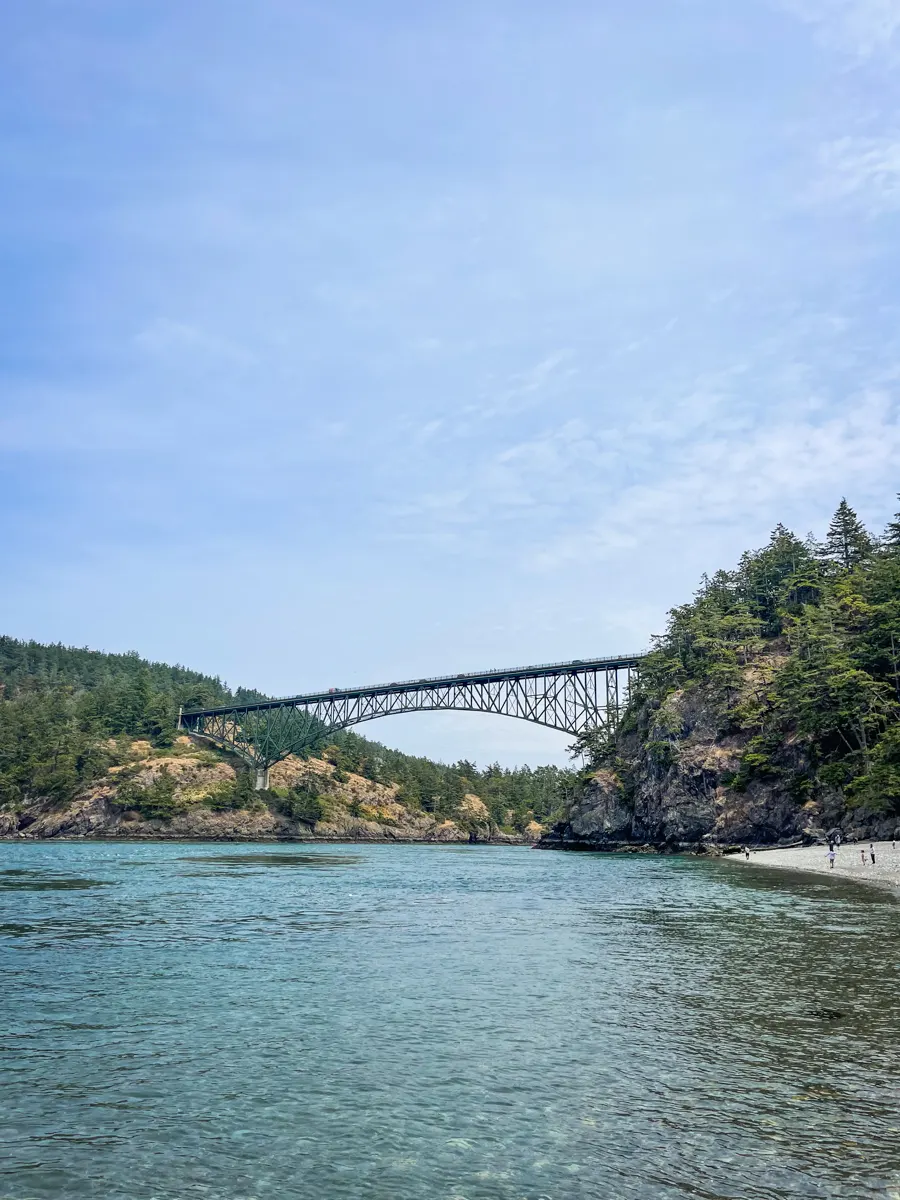 a large steel bridge over a big body of water taken from the beach on one side of the bridge located in Deception Pass State Park on Whidbey Island.