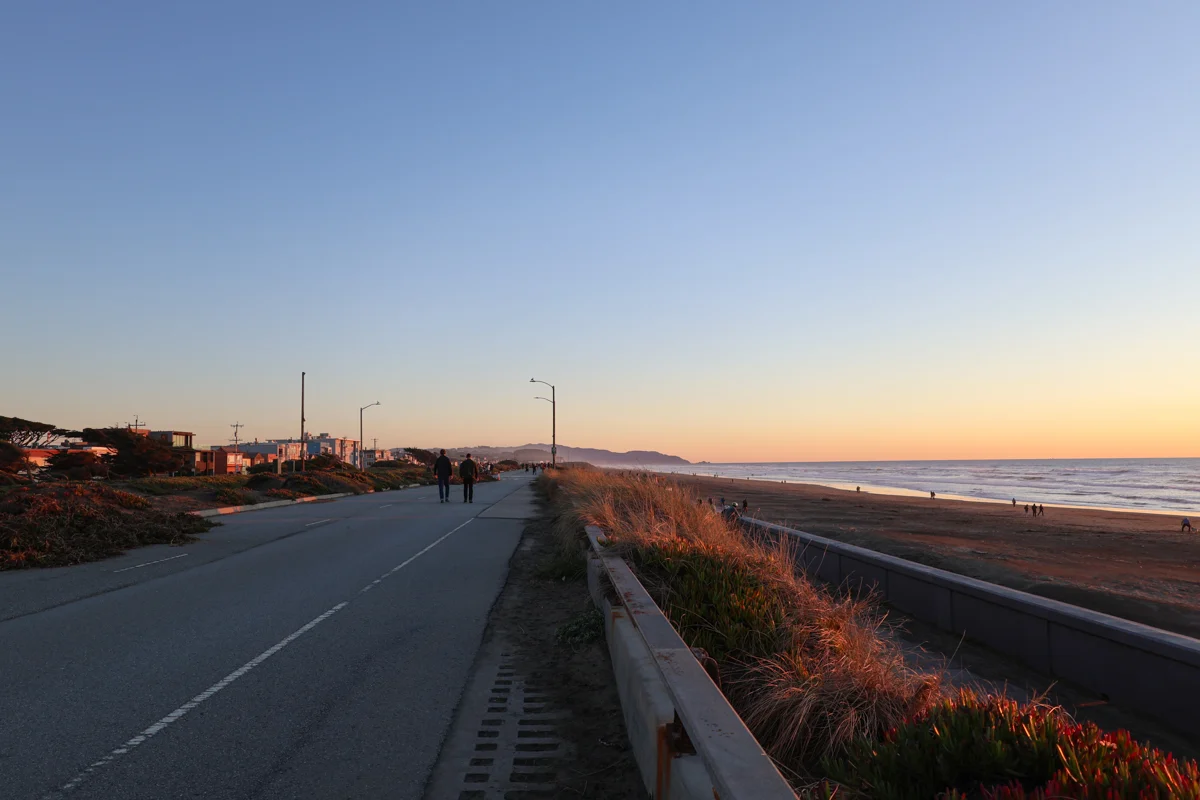 sunset views with the beach to the right and a bike path to the left.