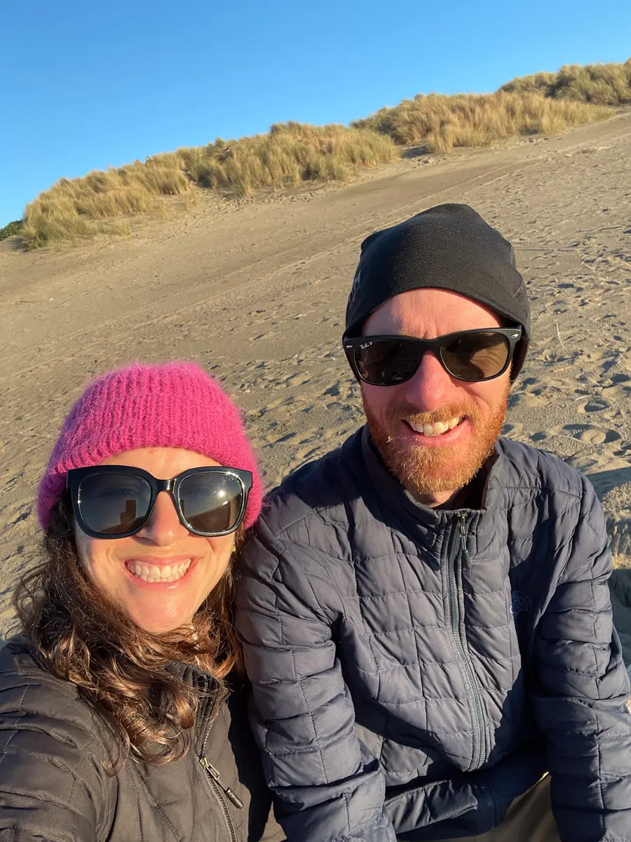 man and woman on the beach in winter hats and sunglasses.