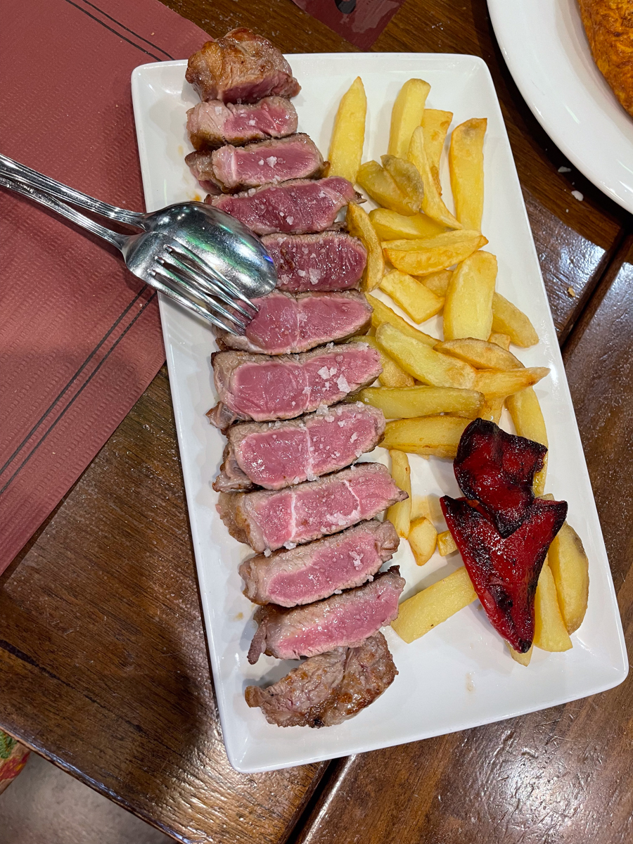sliced up entrecote exposing the rare side of the sliced meat with french fries on the side