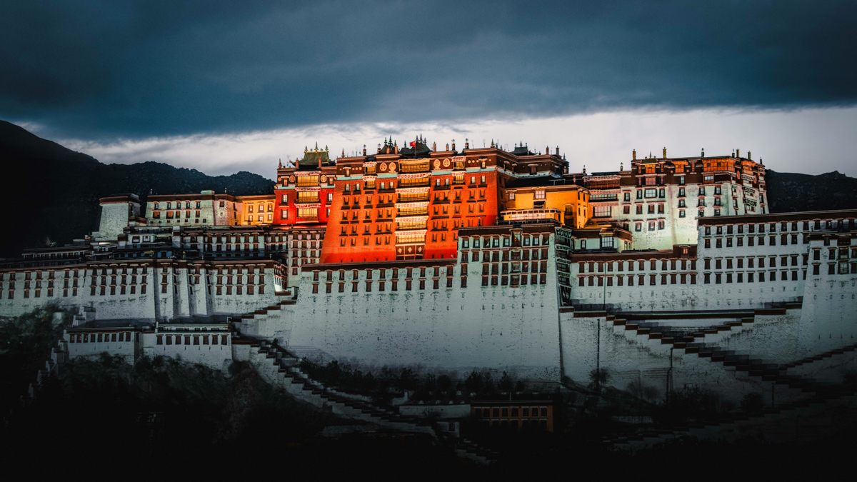 temple and palace in tibet, lit at night to show off the bright orange color of the middle of the temple